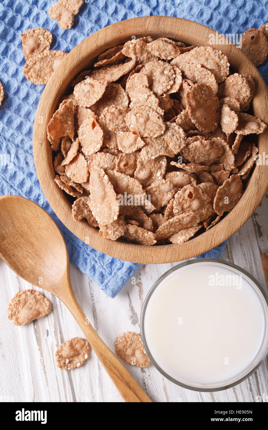 Cereal flakes in a wooden bowl and milk close-up. Vertical view from above Stock Photo