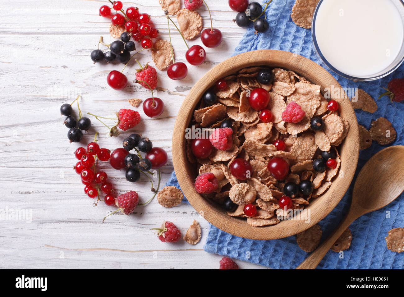 Granola with fresh berries in a wooden bowl and milk on the table. Horizontal top view Stock Photo