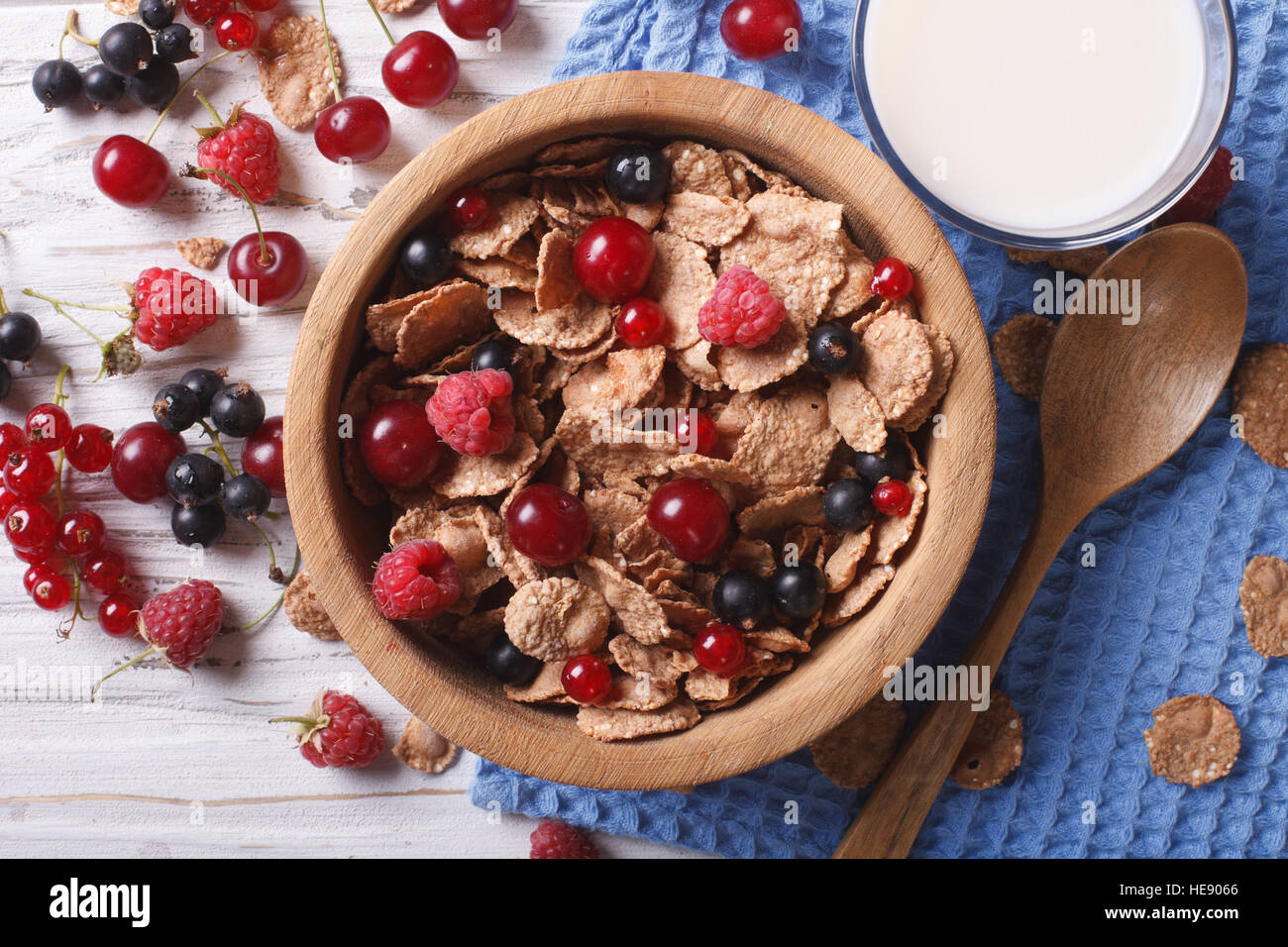 muesli with fresh berries in a wooden bowl and milk on the table. horizontal top view Stock Photo