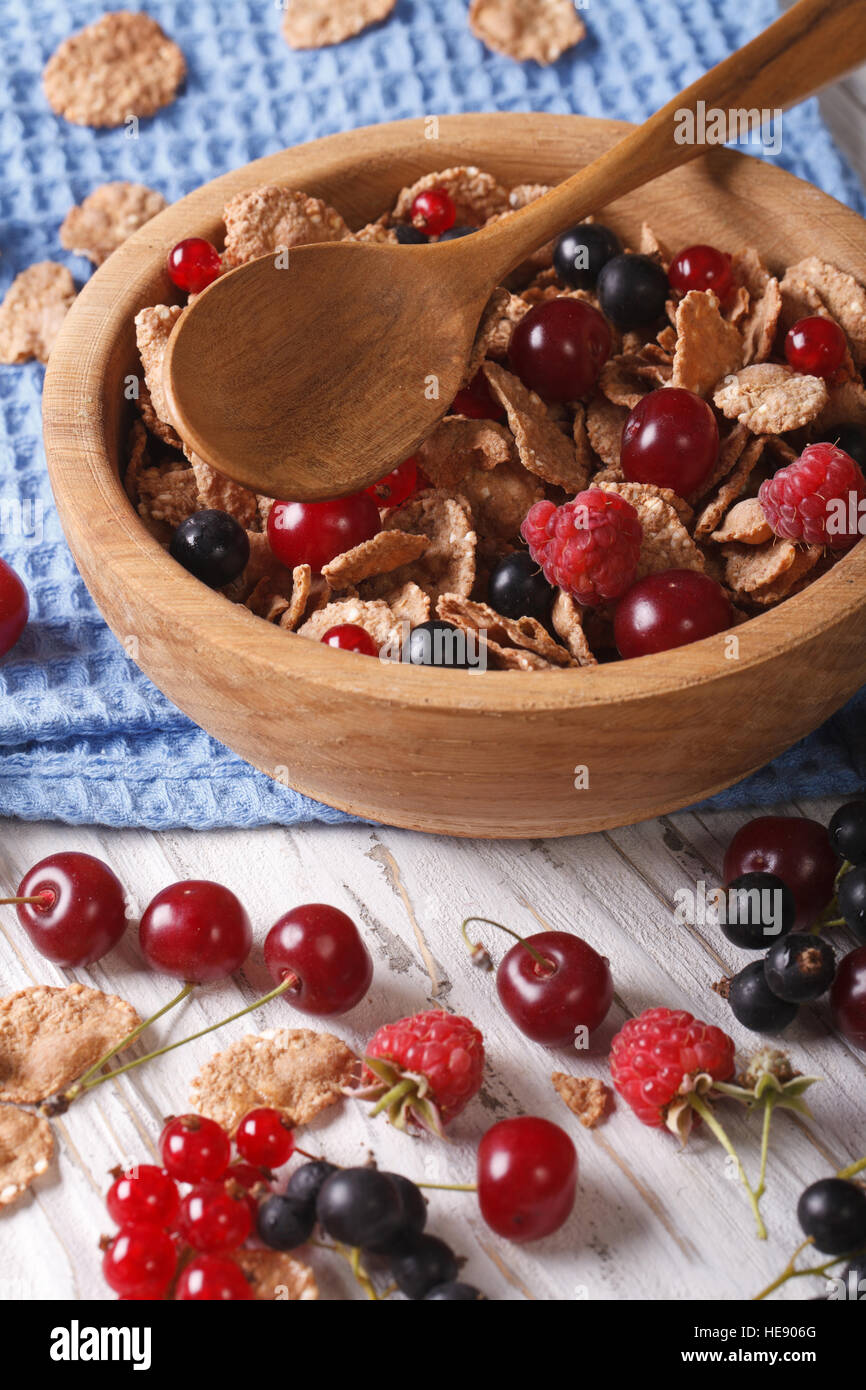 flakes with fresh berries close up in a wooden bowl on the table. vertical Stock Photo