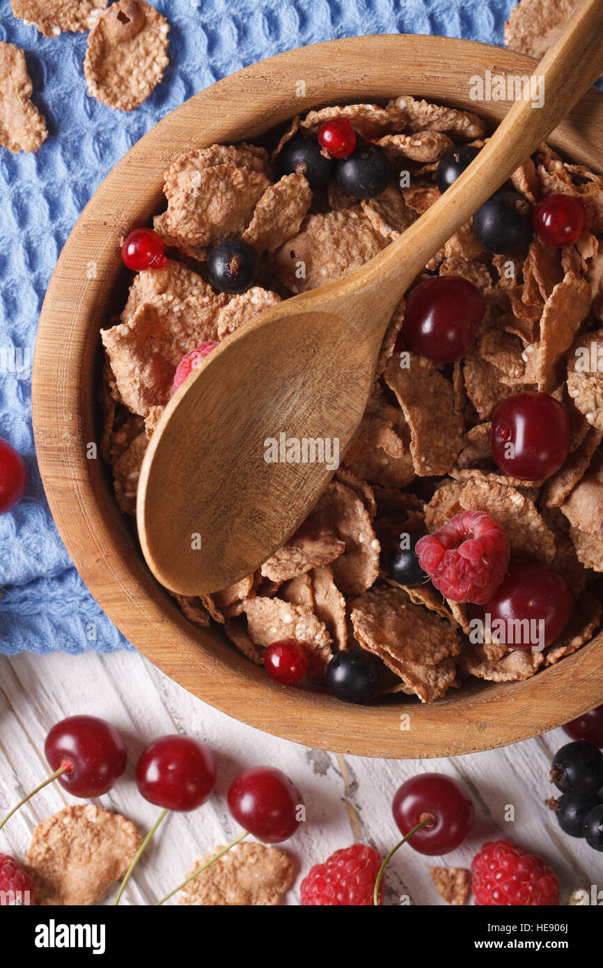 flakes with fresh berries close up in a wooden bowl on the table. Vertical top view Stock Photo