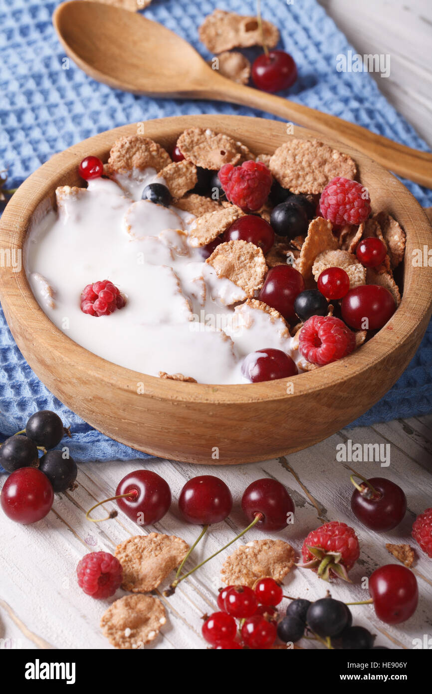 Healthy breakfast: flakes with milk and berries close up in a wooden bowl. Vertical Stock Photo