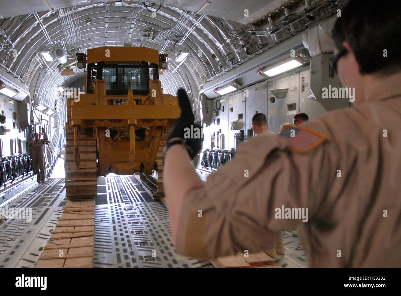 Air Force loadmasters guide cargo, including heavy equipment, into a C ...