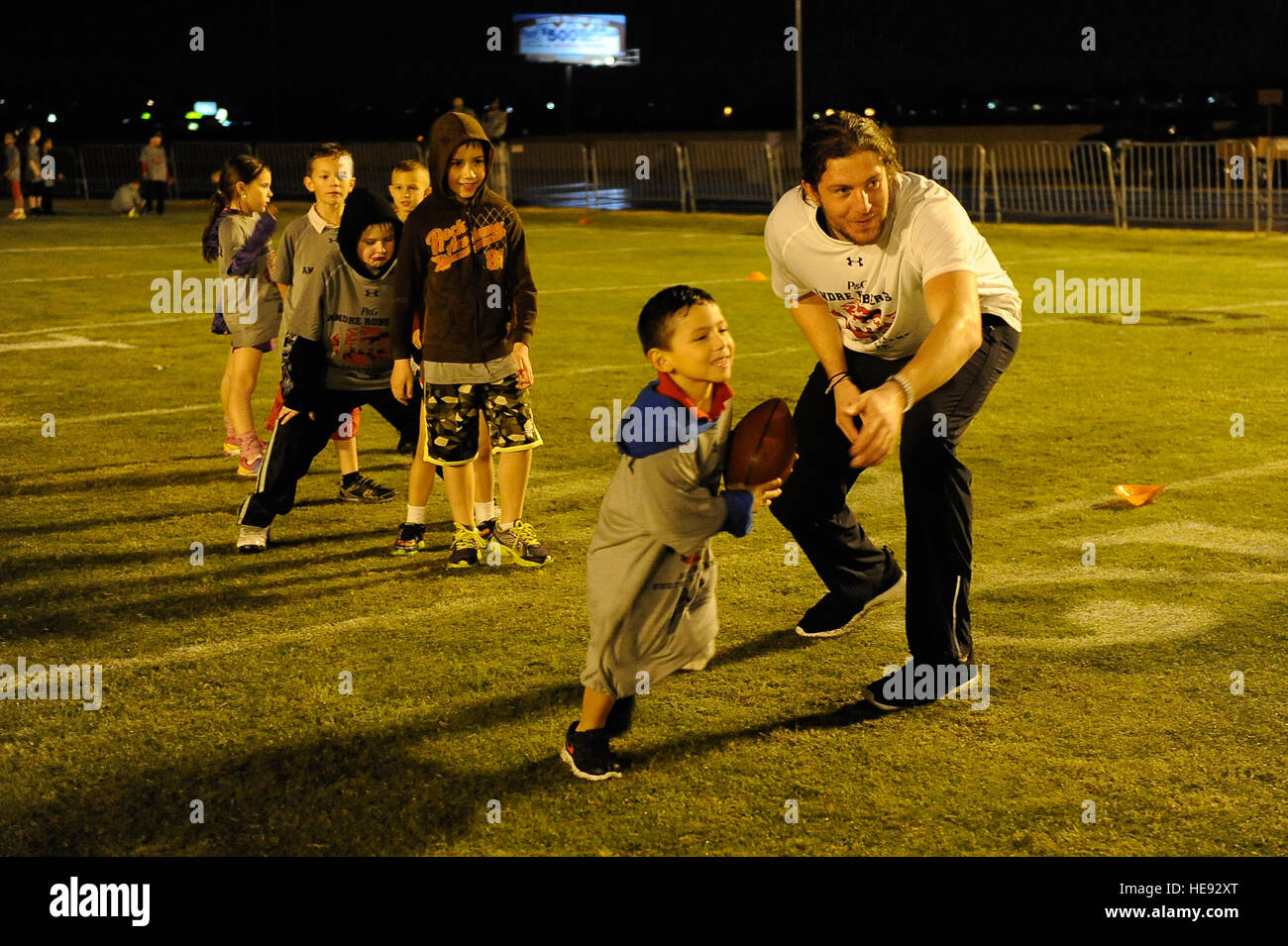 Gabriel Gutierrez, son of Staff Sgt. Arlene Gutierrez, 56th Security Force Squadron, accepts a hand off from New York Jets tight end, Zach Sudfeld during a youth football camp at Luke Air Force Base, Ariz., Jan. 29, 2015. The camp ran by ProCamps Worldwide, specialized in football fundamentals, with campers receiving instruction from NFL players and football coaches from the local area. Staff Sgt. Staci Miller) (Released) Stock Photo