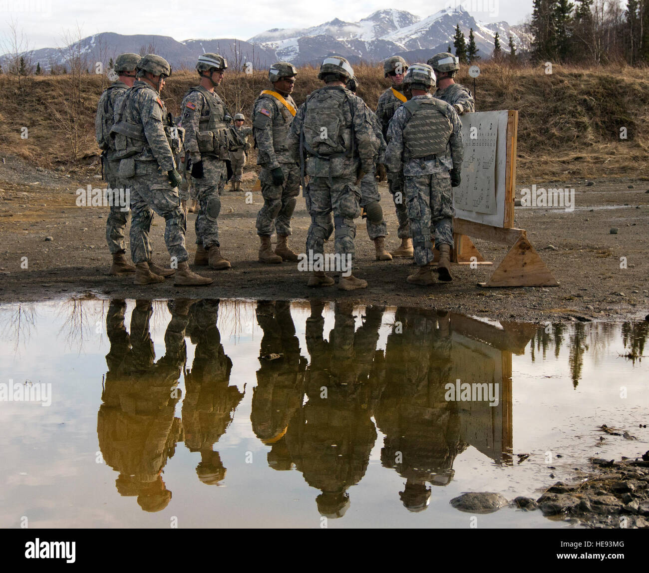 Soldiers of the 23rd Engineer Company, 6th Engineer Battalion (Combat) (Airborne), 2nd Engineer Brigade, U.S. Army Alaska, are seen reflected in a puddle of rain water as they receive instruction while training with the M249 Squad Automatic Weapon, Wednesday, April 23, 2014, on Joint Base Elmendorf-Richardson, Alaska. The M249 is an American adaptation of the Belgian Fabrique Nationale Herstal Minimi, a light machine gun manufactured by the FN Herstal company, and has seen action in every major conflict involving the United States since the U.S. invasion of Panama in 1989. Justin Connaher) Stock Photo