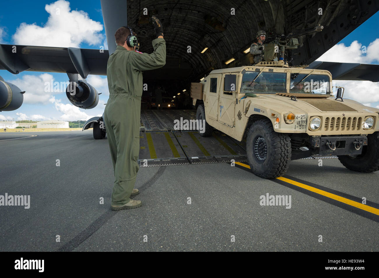 Air Force Staff Sgt. Joe Braunwarth, loadmaster with the 517th Airlift Squadron, Joint Base Elmendorf-Richardson, Alaska, marshals a humvee off of a C-17 Globemaster III as part of a show of force demonstration for Arctic Thunder Open House 2014, July 26, 2014. Arctic Thunder is a biennial event hosted by JBER. Featuring more than 40 Air Force, Army and civilian aerial acts and an expected crowd of more than 200,000 people, it is the largest two-day event in the state and one of the premier aerial demonstrations in the world. The 2014 Arctic Thunder Open House is a proud part of the Anchorage  Stock Photo