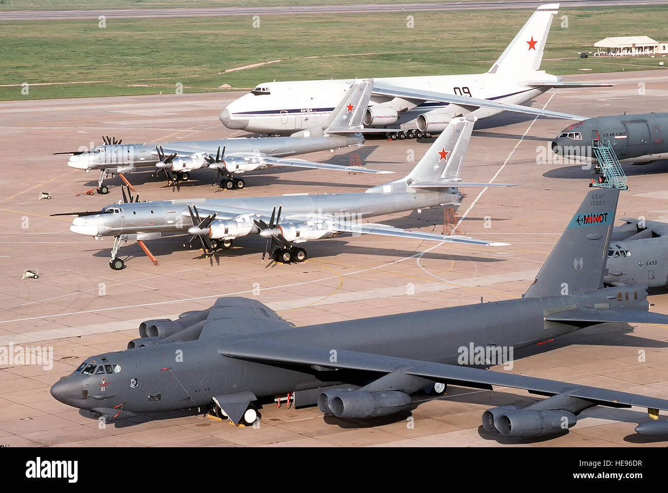 Two Tu-95 Bear bomber aircraft, center, and an AN-124 Condor transport  aircraft of the Russian military, background, are parked on the flight line  beside a B-52H Stratofortress aircraft of the 62nd Bombardment