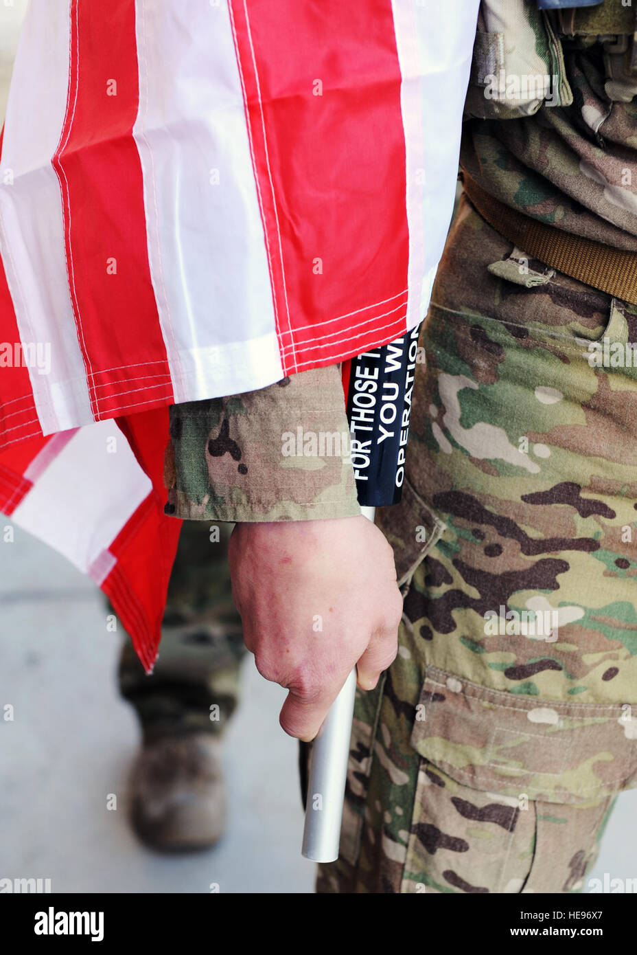 A U.S. Air Force Airman assigned to the 83rd Expeditionary Rescue Squadron holds a U.S. flag bearing the names of seven special operators who were killed March 4, 2002, during Operation Anaconda: U.S. Air Force Senior Airman Jason Cunningham, U.S. Army Cpl. Matthew Commons, U.S. Army Spc. Marc Anderson, U.S. Army Sgt. Phillip Svitak, U.S. Army Sgt. Bradley Crose, U.S. Navy Petty Officer 1st Class Neil Roberts and U.S. Air Force Tech. Sgt. John Chapman, March 3, 2015 at Bagram Air Field, Afghanistan. Service members from all branches conducted a 24-hour vigil run and a retreat ceremony to honor Stock Photo
