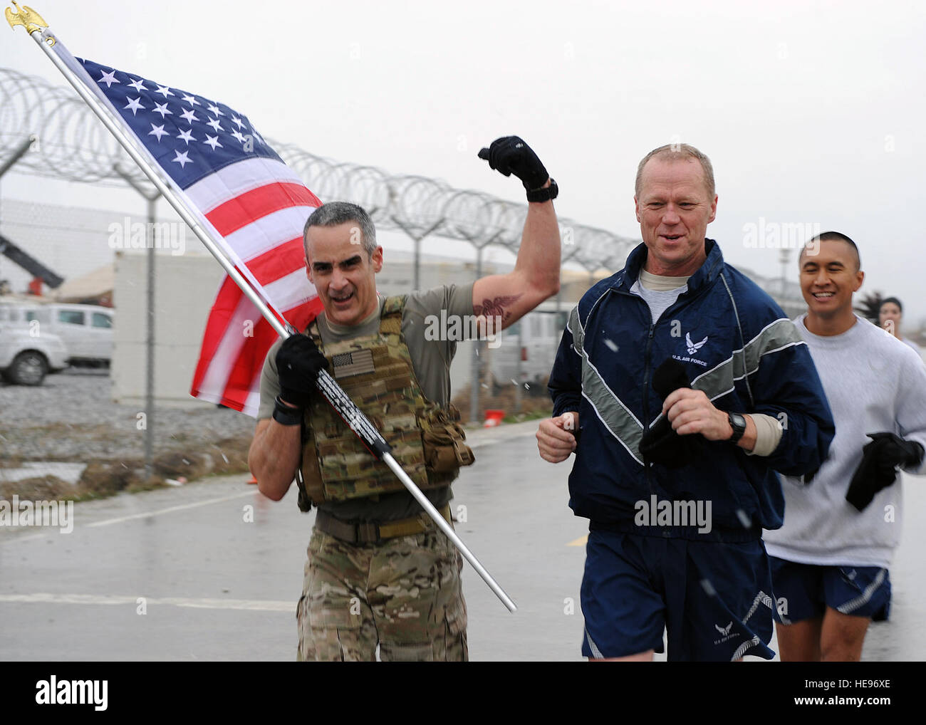 U.S. Air Force Brig. Gen. Mark Kelly, 455th Air Expeditionary Wing commander, and U.S. Air Force Chief Master Sgt. Ramon 'CZ' Colon-Lopez, Air Force Central Command command chief, run with a flag bearing the names of seven special operators who were killed March 4, 2002 during Operation Anaconda: U.S. Air Force Senior Airman Jason Cunningham, U.S. Army Cpl. Matthew Commons, U.S. Army Spc. Marc Anderson, U.S. Army Sgt. Phillip Svitak, U.S. Army Sgt. Bradley Crose, U.S. Navy Petty Officer 1st Class Neil Roberts and U.S. Air Force Tech. Sgt. John Chapman, March 4, 2015 at Bagram Air Field, Afghan Stock Photo