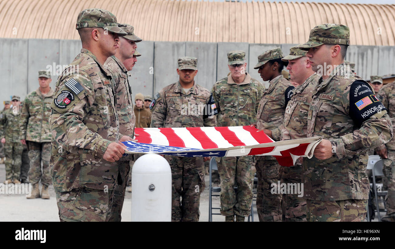 U.S. Air Force Airmen assigned to the base honor guard team prepare to fold the flag during a retreat ceremony honoring special operators who were killed March 4, 2002 during Operation Anaconda: U.S. Air Force Senior Airman Jason Cunningham, U.S. Army Cpl. Matthew Commons, U.S. Army Spc. Marc Anderson, U.S. Army Sgt. Phillip Svitak, U.S. Army Sgt. Bradley Crose, U.S. Navy Petty Officer 1st Class Neil Roberts and U.S. Air Force Tech. Sgt. John Chapman, March 4, 2015 at Bagram Air Field, Afghanistan. Service members from all branches conducted a 24-hour vigil run and a retreat ceremony to honor  Stock Photo