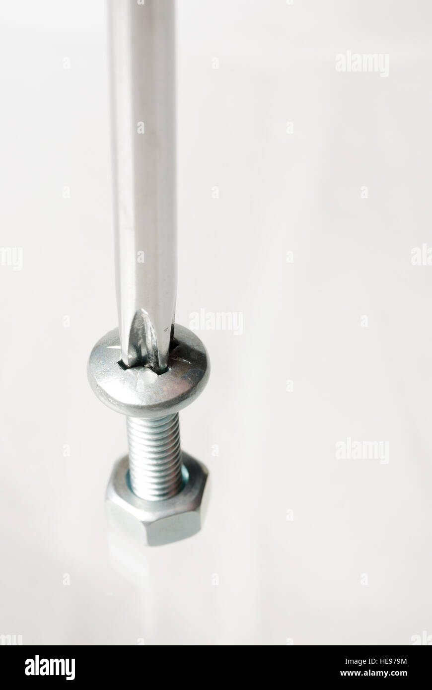 Screwdriver inserted into a bolt with a nut Stock Photo