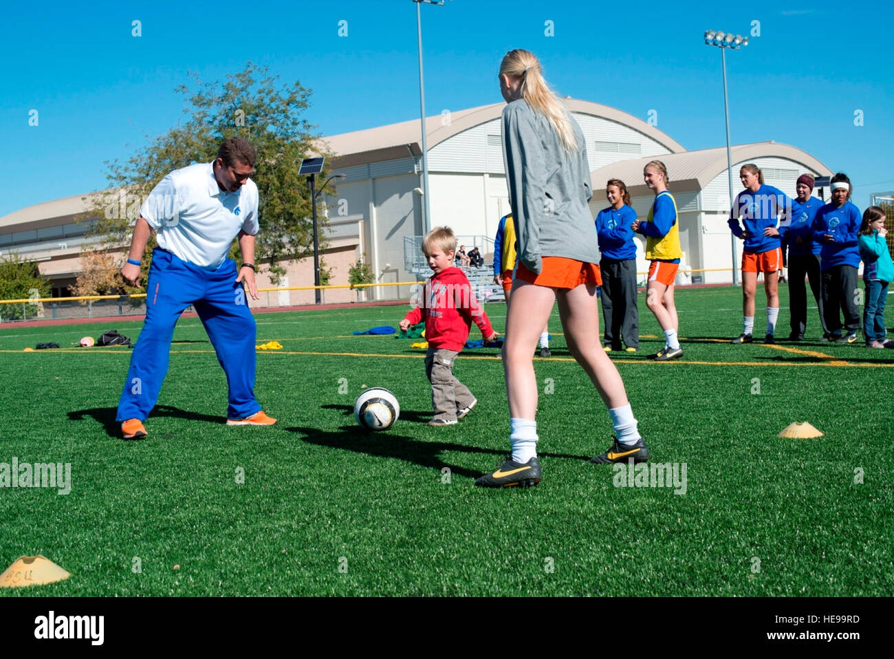 131005-F-WU507-032:  Three-year-old Elijah Carlsness, son of Tech. Sgt. Tim Carlsness, 366th Operations Support Squadron, dribbles a ball between a Boise State University ladies soccer player and Ed Moore, Broncos assistant coach at Mountain Home Air Force Base, Idaho, Oct. 5, 2013. The Broncos visited base to show appreciation for military members, heard a few real-life combat experiences and hosted a free clinic for family members.  Master Sgt. Kevin Wallace/) Stock Photo