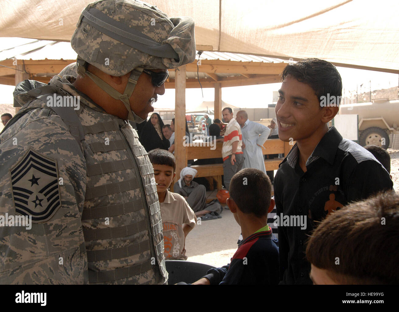 Camp Bucca, Iraq -- Chief Master Sgt. Jeffrey Antwine, 386th Air Expeditionary Wing command chief, jokes with a young Iraqi boy waiting to visit his father at the Theater Internment Facility (TIF) at Camp Bucca, Iraq, on Sept. 29. The 887th Expeditionary Security Forces Squadron controls access to prisoners at the TIF and processes visitation procedures for family members. The Air Force works side by side with Army Soldiers in manning the facility, which houses more than 18,000 inmates. Tech. Sgt. Raheem Moore) Stock Photo