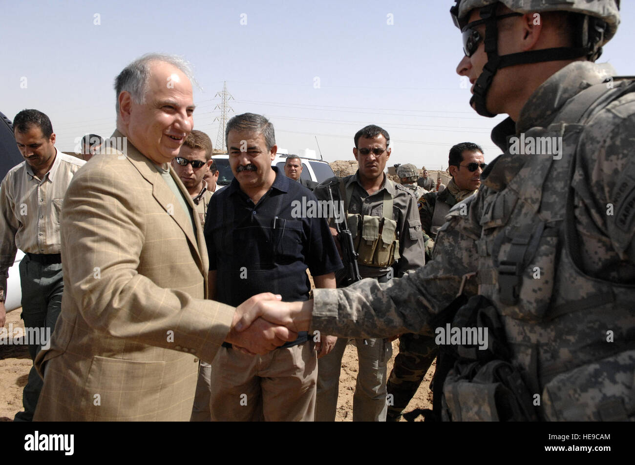 Dr. Ahmed Chalabi, leader of the Iraqi national congress, is met by U.S. Army Capt. Will Boyd, from 2nd Stryker Brigade Combat Team, 25th Infantry Division, upon arrival to a water access point in the Taji Qada, Iraq, on March 20, 2008. Stock Photo