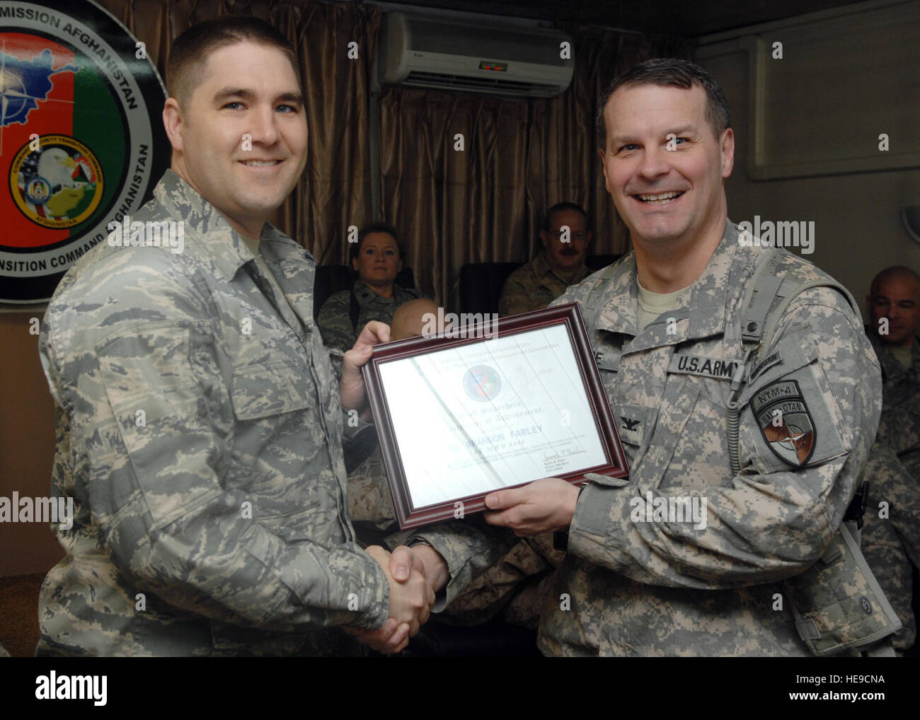 CAMP EGGERS, Afghanistan (May, 8, 2010)--NATO Training Mission-Afghanistan Chief of Staff Col. Joseph Buche presents the Staff Superhero Certificate of Achievement  to Special Agent Brandon Farley from CJ7 for his accomplishements while deployed and working for NTM-A.  Staff Sgt. Jeff Nevison) Stock Photo