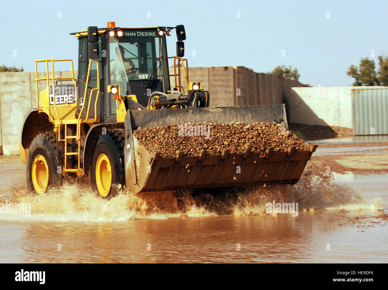 A front end loader plows through a flooded area of Joint Base Balad, Iraq, with a load of rock to build up low areas Oct. 25. Because rain is infrequent in Iraq, when it does rain, the hardened ground soaks up little water. Tech. Sgt. Erik Gudmundson) Stock Photo