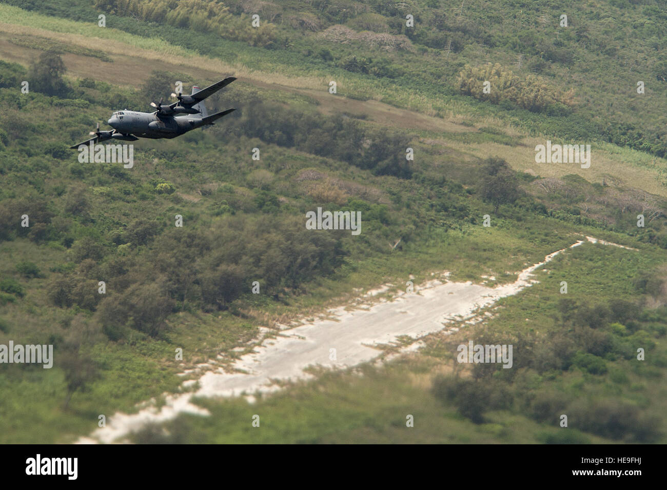 A U.S. Air Force C-130H Hercules flies over North Field, Tinian, Marianna Islands, during Cope North 15, Feb. 26, 2015. North Field served as the World War II headquarters for the 509th Composite Group that launched the atomic bomb attacks against Hiroshima and Nagasaki, Japan, in August of 1945. Through training exercises such as Exercise Cope North 15, the U.S., Japan and Australia air forces develop combat capabilities, enhancing air superiority, electronic warfare, air interdiction, tactical airlift and aerial refueling.  Tech. Sgt. Jason Robertson Stock Photo