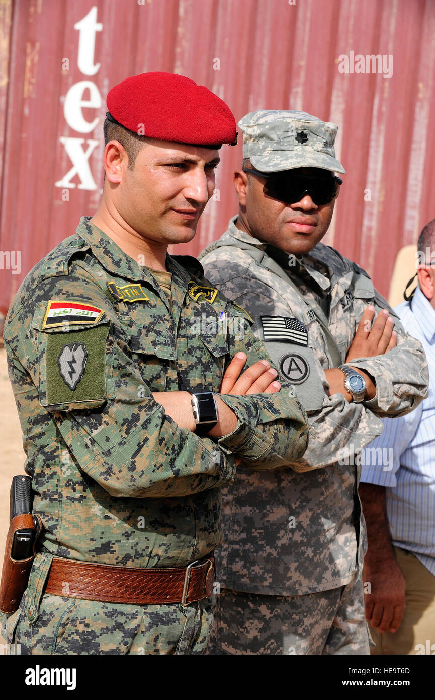 An Iraqi soldier and U.S. Solider stand together as they are briefed by Navy Explosive Ordinance Disposal  personnel during a counter improvised explosive device demonstration on Contingency Operating Base Speicher in northern Iraq, Oct. 6. The demonstration included a controlled detonation of an improvised explosive device and showed the techniques and equipment used by EOD personnel to secure, process and investigate blast sites by collection and analysis of key evidence pieces found post IED blast. Stock Photo