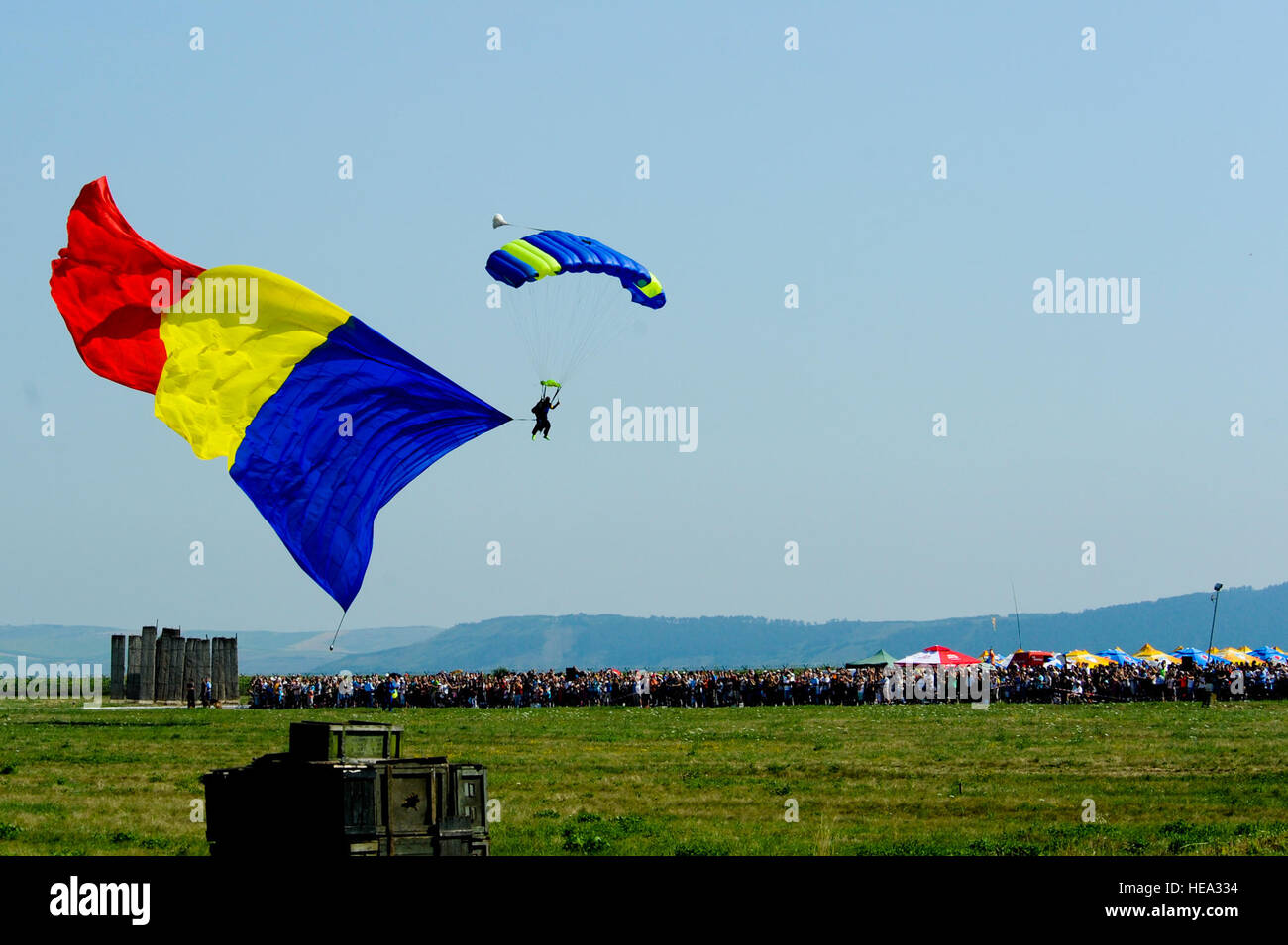 A parachutist floats to the ground while bearing a large Romanian flag before hundreds of spectators during the Romanian air force's 71st Air Base's air show and open house at Campia Turzii, Romania, July 23, 2016. The aviation demonstration took place during the middle of the U.S. Air Force's 194th Expeditionary Fighter Squadron's six-month long theater security package deployment to Europe in support of Operation Atlantic Resolve, which aims to bolster the U.S.'s continued commitment to the collective security of NATO and dedication to the enduring peace and stability in the region. The unit Stock Photo
