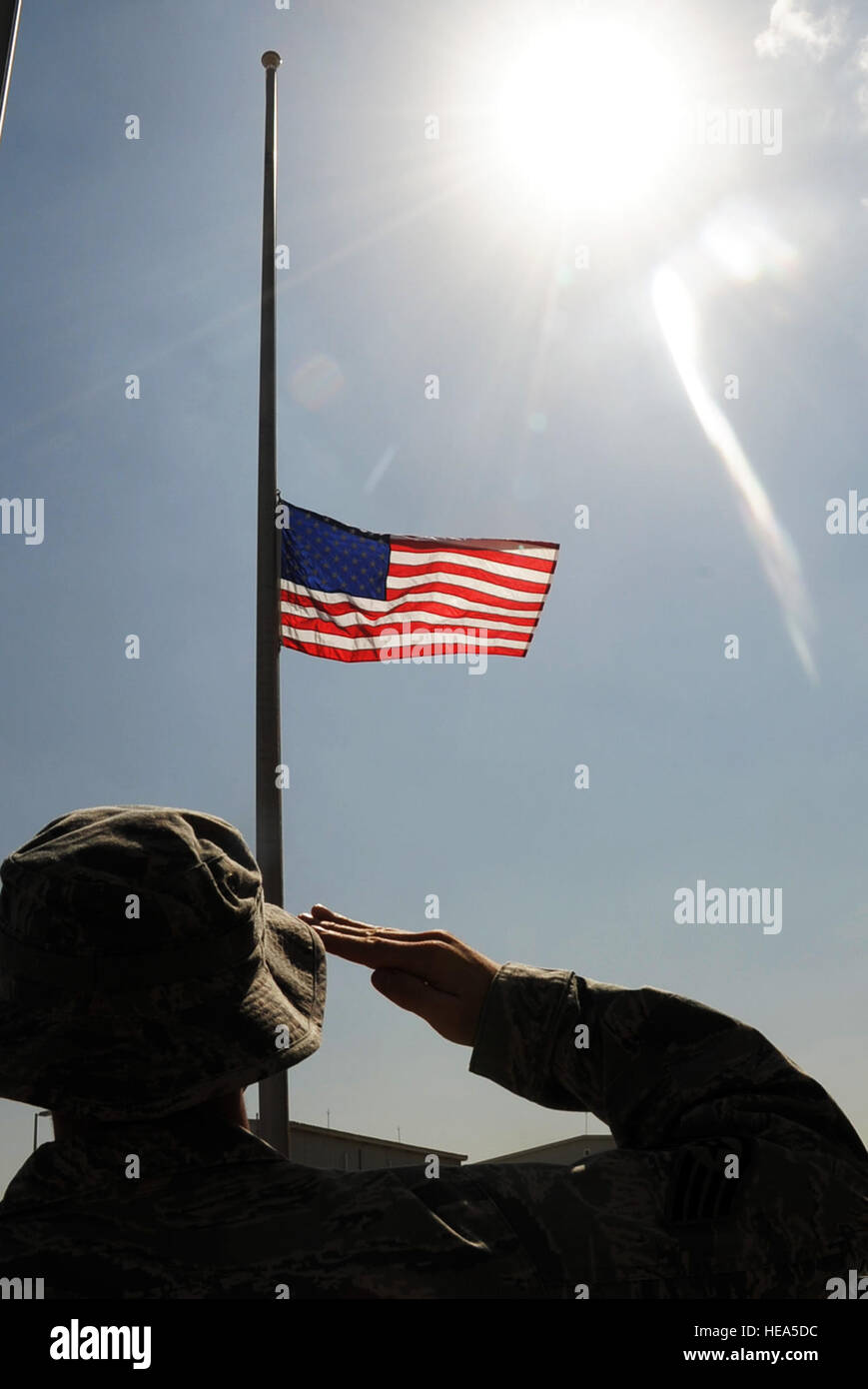 An Airman assigned to the 380th Air Expeditionary Wing at a non-disclosed base in Southwest Asia salutes the American flag Feb. 9, 2010, that is flying at half-mast in honor of U.S. Representive John Murtha of Pennsywho died on Feb. 8. Representative Murtha was a military veteran who earned the Bronze Star and two Purple Hearts during the Vietnam War. Military installations around the world flew the flag at half-mast Feb. 9 in honor of Representative Murtha by declaration from President Barack Obama. (U.S. Air Force Photo/Master Sgt. Scott T. Sturkol Stock Photo