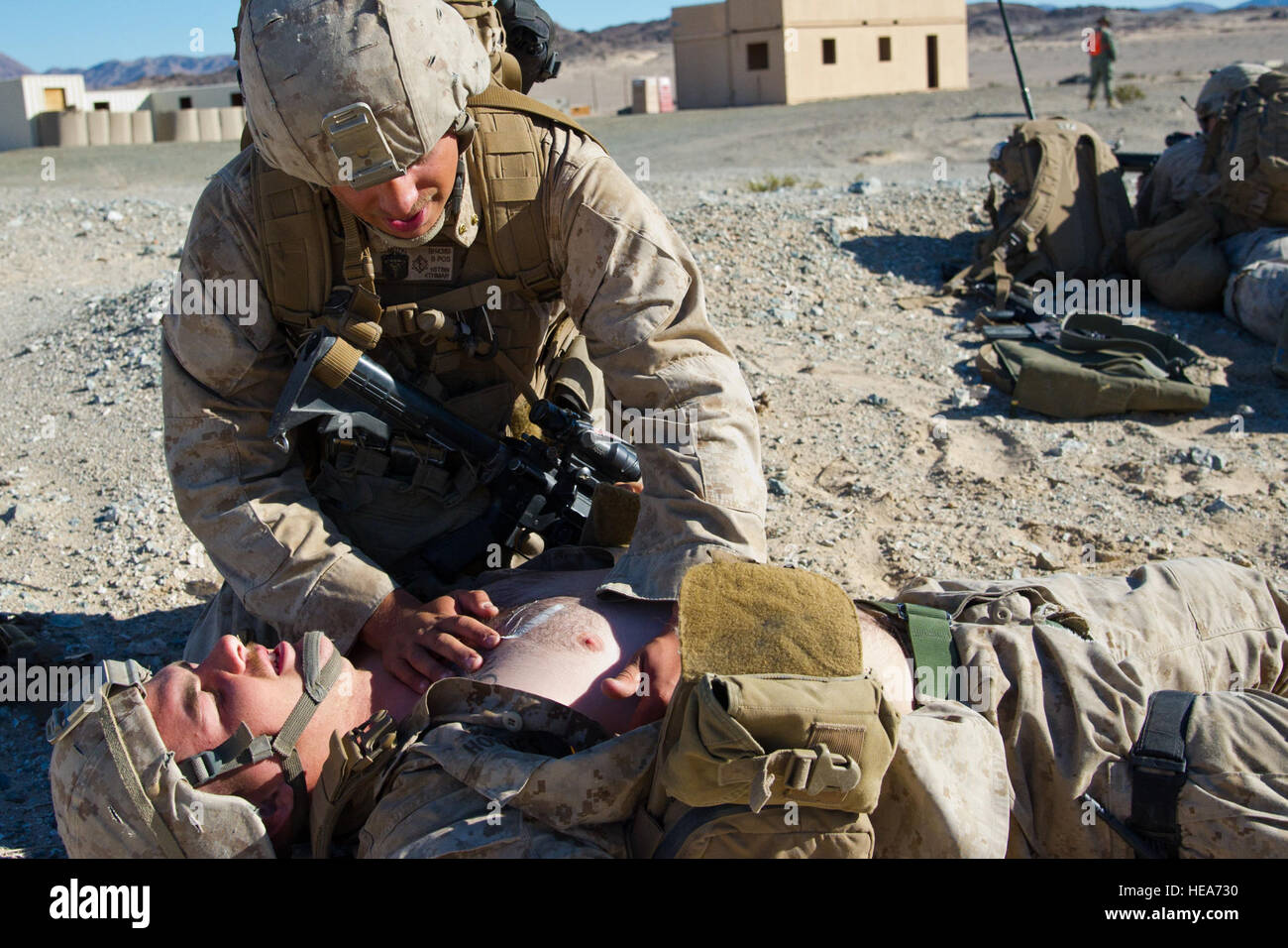 U.S. Marine Cpl. Joshua Trivino (left) and U.S. Navy Hospitalman Matthew Holomuzki (right) perform a two man carry on a simulated victim Marine Cpl. David Hommes (center), all assigned to Company B, 1st Battalion, 4th Marine Regiment, Marine Corps Base Camp Pendleton, Calif., during Integrated Training Exercise 2-15 at Marine Corps Air Ground Combat Center (MCAGCC) Twentynine Palms Calif., Feb. 17, 2015. MCAGCC conducts relevant live-fire combined arms training, urban operations, and Joint/Coalition level integration training that promote operational forces readiness.  Staff Sgt. Kyle Brasier Stock Photo