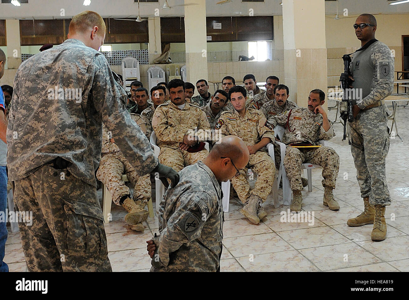 U.S. Army Staff Sgt. Chris Branam, from Odessa, Texas, demonstrates how to perform a personnel search on U.S. Army Capt. Paul Dixon, from Charlotte, N.C., for the soldiers of the Iraqi Shurta, Department of Border Enforcement Team, as U.S. Army Sgt. 1st Class Jonathan Kirksey, demonstrates how and where security is needed during the search, as part of the body search class, in Basra, Iraq, Sept. 2.  U.S. Soldiers of the 1st Commando Battalion, Battalion Transition Team, teach the courses to instill self-confidence in self-defense, map reading, the global positioning system, first-aid and perso Stock Photo