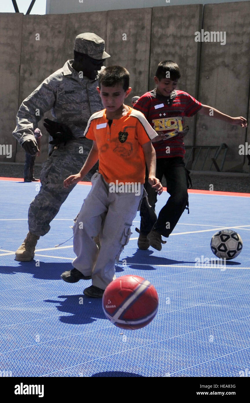 An Airman plays kickball with two Iraqi boys during Iraqi Kids Day at Joint Base Balad, Iraq, April 24. This was the first Iraqi Kids Day of 2010 and it serves as part of the ongoing base effort to positively engage the local populace. Thirty-four children from a local orphanage were bussed onto base to play games, share culture and to have a day of fun. Stock Photo