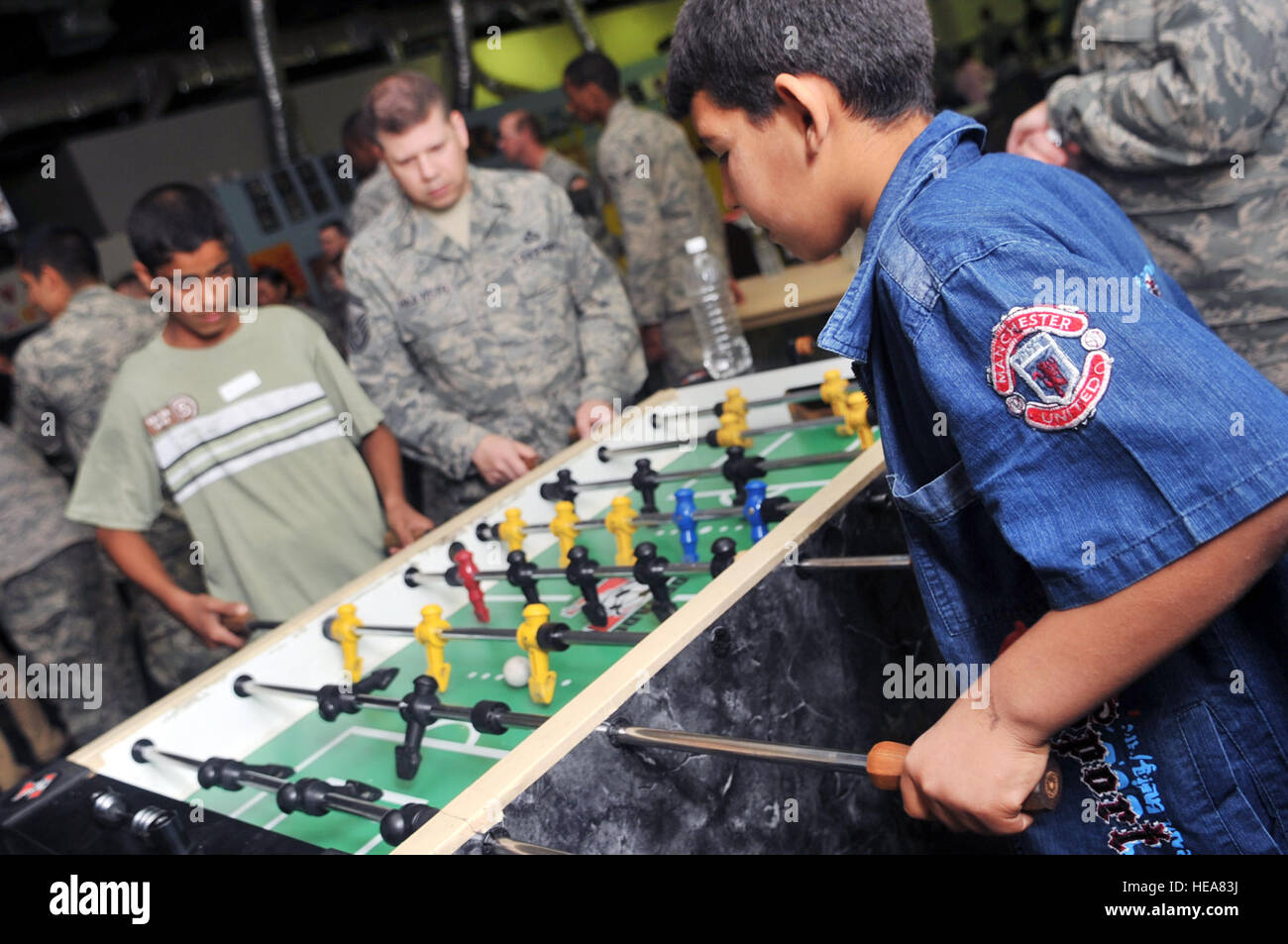 Senior Master Sgt. James Haavisto, 332nd Expeditionary Operations Support Squadron weather flight NCO in charge, plays a game of foosball with two Iraqi boys during Iraqi Kids Day at Joint Base Balad, Iraq, April 24. This was the first Iraqi Kids Day of 2010 and it serves as part of the ongoing base effort to positively engage the local populace. Thirty-four children from a local orphanage were bussed onto base to play games, share culture and to have a day of fun. Stock Photo