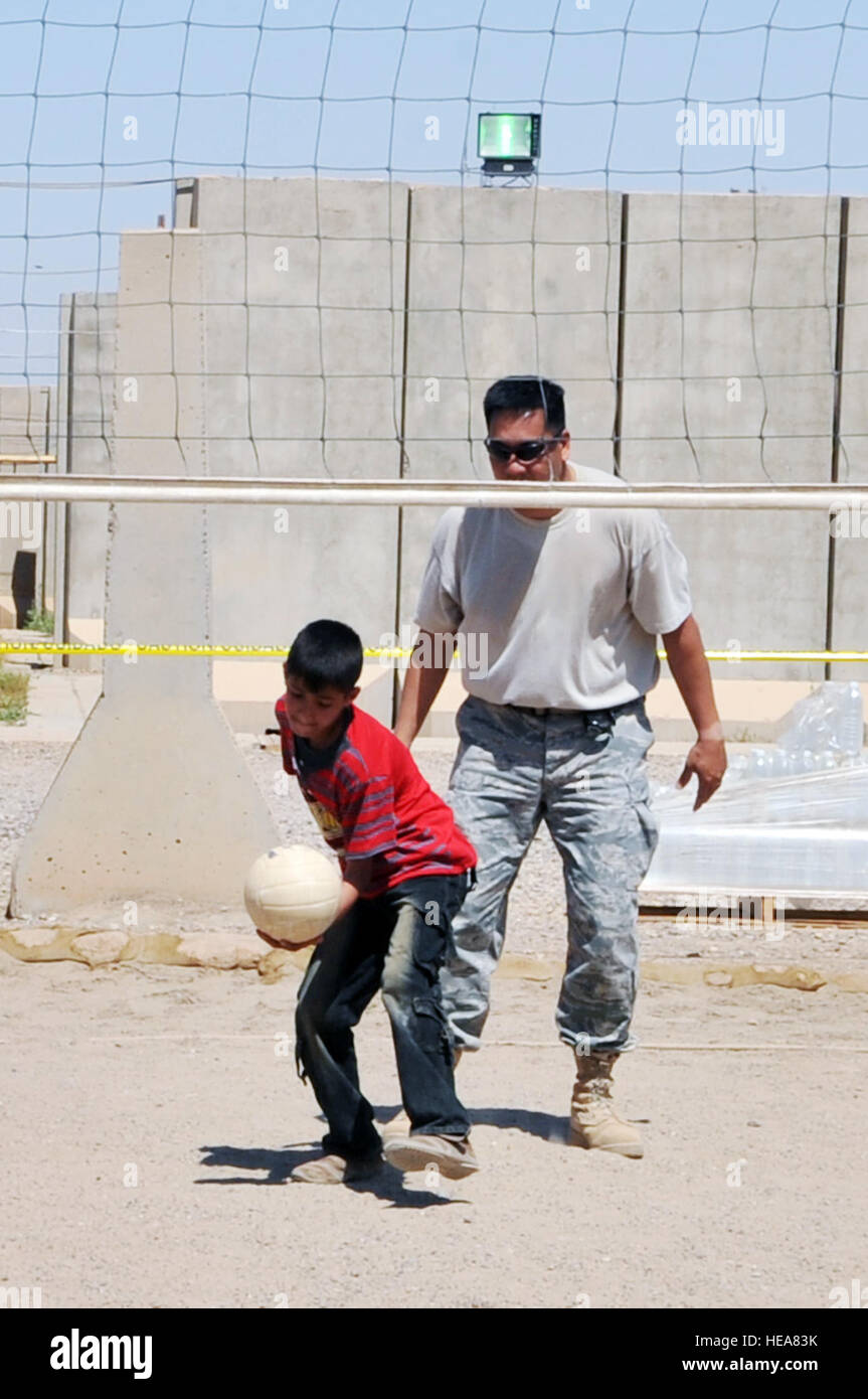 Tech. Sgt. Joseph Ferrer, 332nd Expeditionary Civil Engineer Squadron construction manager, plays volleyball with an Iraqi boy during Iraqi Kids Day at Joint Base Balad, Iraq, April 24. This was the first Iraqi Kids Day of 2010 and it serves as part of the ongoing base effort to positively engage the local populace.  Thirty-four children from a local orphanage were bussed onto base to play games, share culture and to have a day of fun. Stock Photo