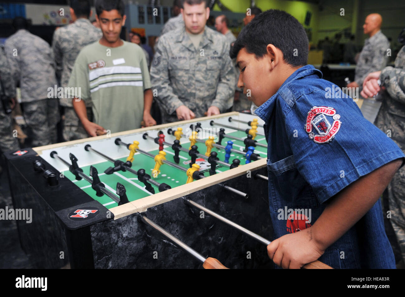 Senior Master Sgt. James Haavisto, 332nd Expeditionary Operations Support Squadron weather flight NCO in charge, plays a game of foosball with two Iraqi boys during Iraqi Kids Day at Joint Base Balad, Iraq, April 24. This was the first Iraqi Kids Day of 2010 and it serves as part of the ongoing base effort to positively engage the local populace. Thirty-four children from a local orphanage were bussed onto base to play games, share culture and to have a day of fun. Stock Photo