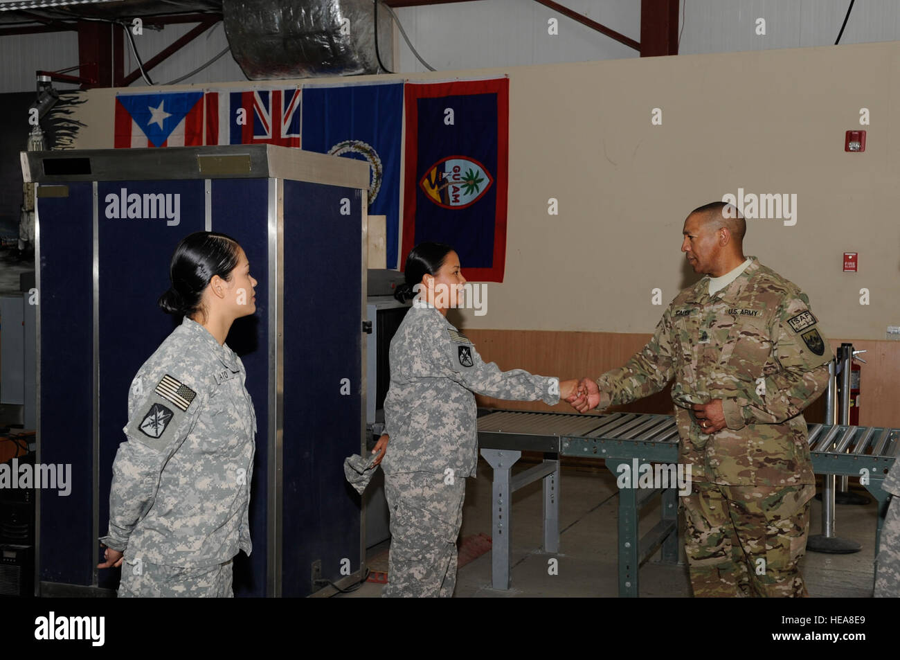 Army Command Sgt. Maj. Thomas Capel, International Security Assistance Force and United States Forces - Afghanistan senior enlisted adviser presents a superior performer coin to Spc. Kellie Mantanona during a tour of the Transit Center at Manas, Kyrgyzstan, Aug. 1, 2012. Mantanona serves as a customs agent at the Transit Center and is assigned to the 368th Military Police Company, Detachment 4. She is currently deployed from the U.S. Army Reserve Center, Barrigada, Guam. Stock Photo