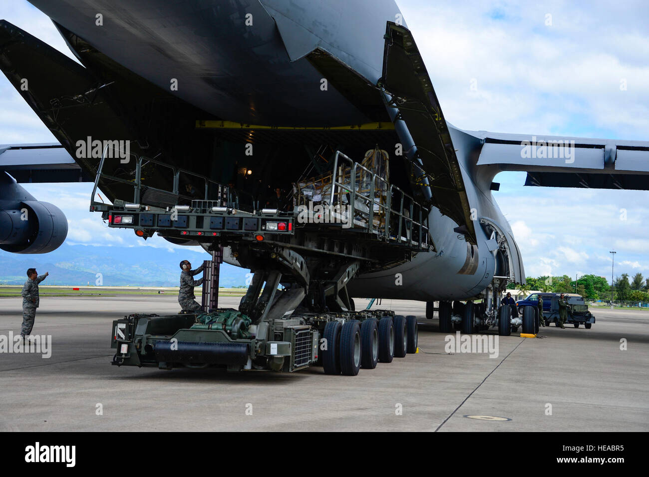 Crew members of a C-5 Galaxy from Westover Air Reserve Base, Mass., and members from the 612th Air Base Squadron unload a shipment of donated goods at Soto Cano Air Base, Honduras, Oct. 11, 2014. The cargo transporting aircraft delivered over 6,000-pounds of humanitarian aid and supplies that were donated to Honduran citizens in need through the Denton Program.  The Denton Program allows private U.S. citizens and organizations to use space available on U.S. military cargo planes to transport humanitarian goods to approved countries in need. Tech. Sgt. Heather Redman) Stock Photo
