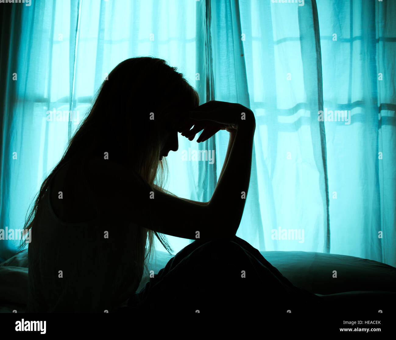 Silhouette of woman sitting in bed by window Stock Photo