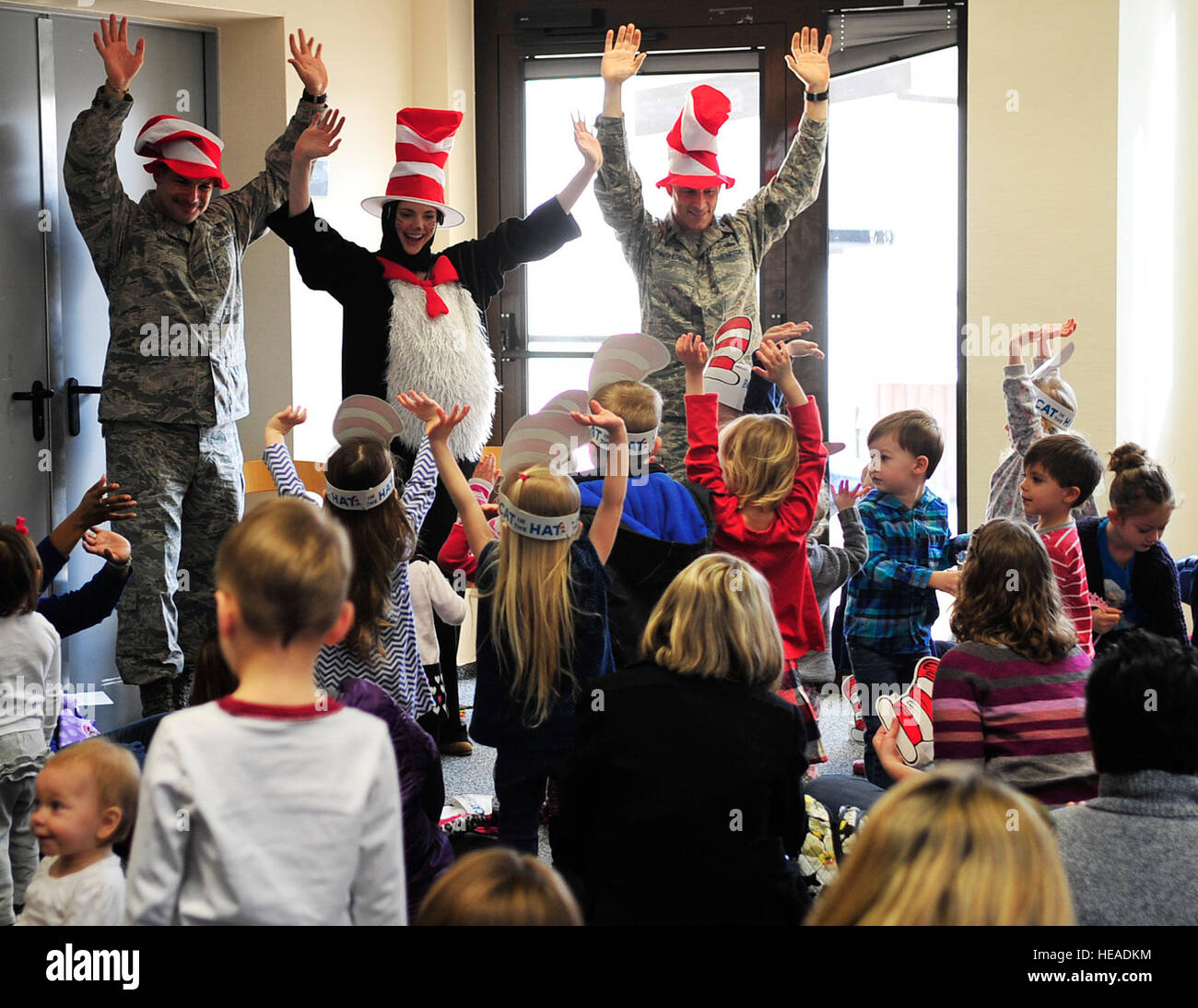 Chief Master Sgt. Steven Mandell, (left), 86th Force Support Squadron superintendent, Alison McKee, 86th FSS librarian, and Lt. Col. Thomas Ausherman, (right), 86th FSS commander, lead children through a song and dance during Read Across America, March 5, 2015, at Ramstein Air Base, Germany. The event consisted of story time, snacks and free books for the children. Airman 1st Class Larissa Greatwood) Stock Photo