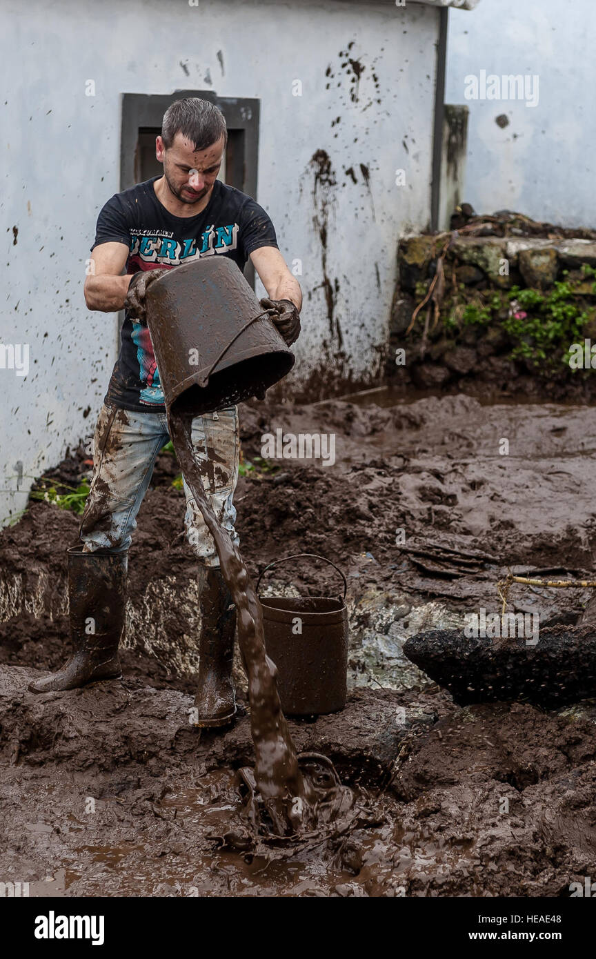 Nelson Silveira lends a hand to remove mud from his neighbor’s home. Airmen from the 65th Operations Support Squadron and other units from Lajes Field volunteered to remove water and mud from homes and businesses following severe rain and flooding in Porto Judeu, Azores, Mar. 15, 2013. Roughly 30 homes were damaged from the flooding.  Lucas Silva) Stock Photo
