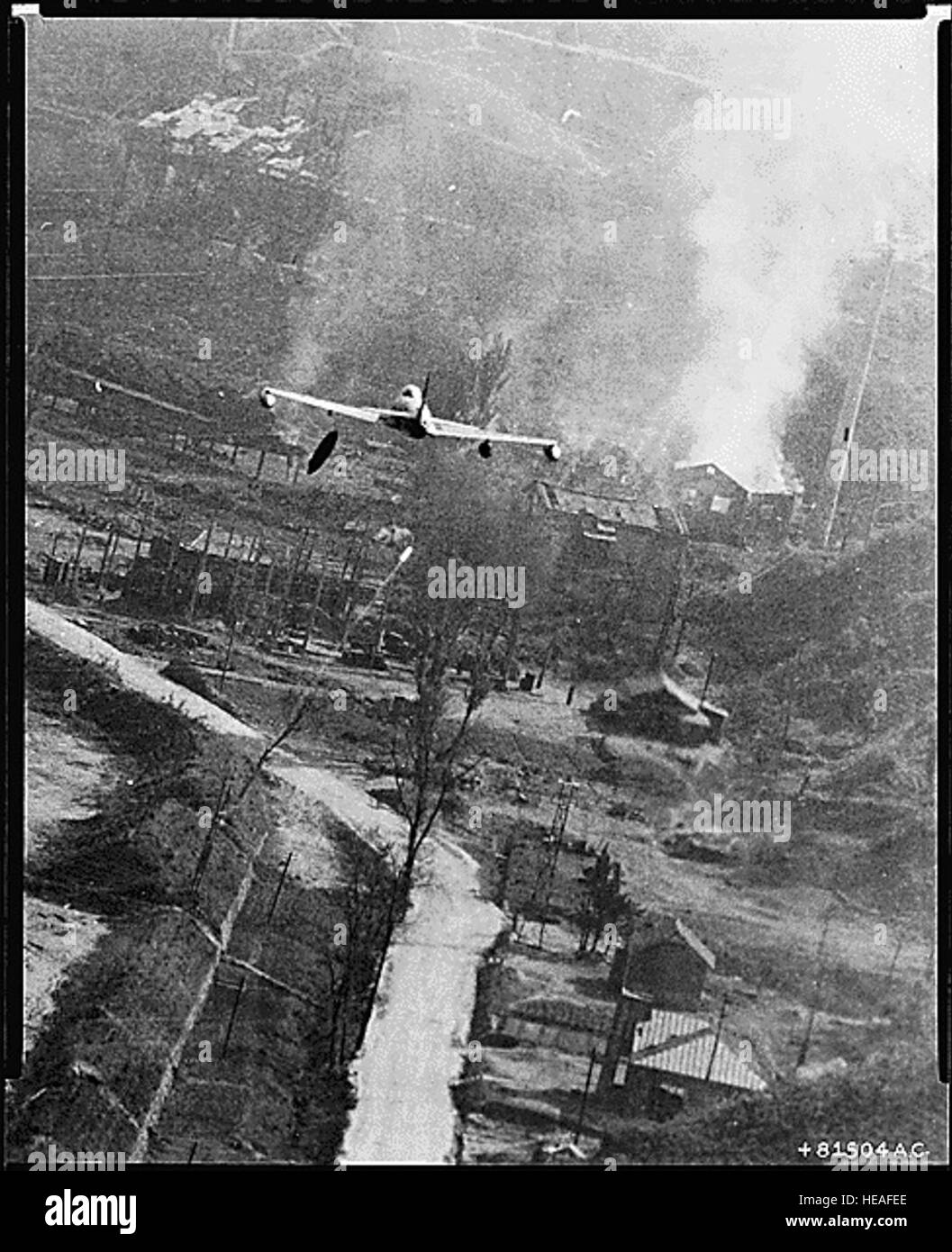 Korean War Pictures - An F-80 Dropping Napalm Bombs at Suan This dramatic photo of a U.S. Air Force F-80 Shooting Star fighter-bomber has captured the action which occurred May 8 when day-long flights of Fifth Air Force warplanes blasted the Communist two-square mile supply center at Suan in the largest single air strike of the Korean conflict. The storage area, 35 miles southeast of Pyongyang, was smothered with more than 12,000 gallons of napalm dropped by the attacking planes. In this photo a tank of napalm can be seen just after being released. It is below the left wing of the jet. Target Stock Photo