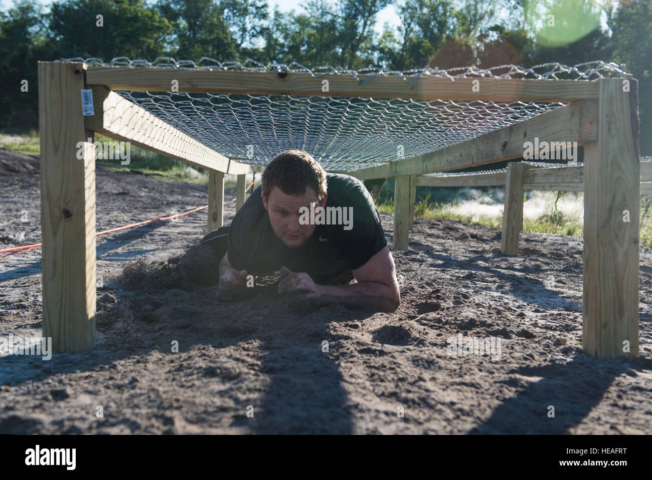 A runner low crawls through an obstacle during the 2015 Moody Mudder May 2, 2015, in Ray City, Ga. Runners participated in many obstacles throughout the run such as a climbing wall, fire pit, low crawls, monkey bars and rock hills.  Airman 1st Class Dillian Bamman Stock Photo