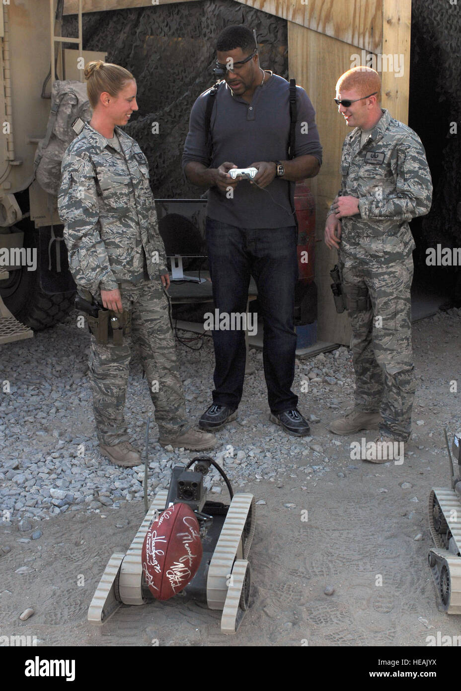 Fox NFL Sunday's Michael Strahan learns to operate an explosive ordnance disposal robot at Bagram Airfield, Afghanistan, Nov. 6, 2009, from Staff Sgt. Elizabeth Spradley (left) and Senior Airman James Dobrynski, both EOD technicians with the 755th Air Expeditionary Group, based at Bagram Airfield, Afghanistan.  The two EOD Airmen had Mr. Strahan practice picking up an autographed NFL football.  Sergeant Spradley is deployed from Spangdahlem Air Base, Germany. Airman Dobrynski is deployed from Luke Air Force Base, Ariz. The FOX NFL team is scheduled to broadcast live from here Nov. 8. The team  Stock Photo
