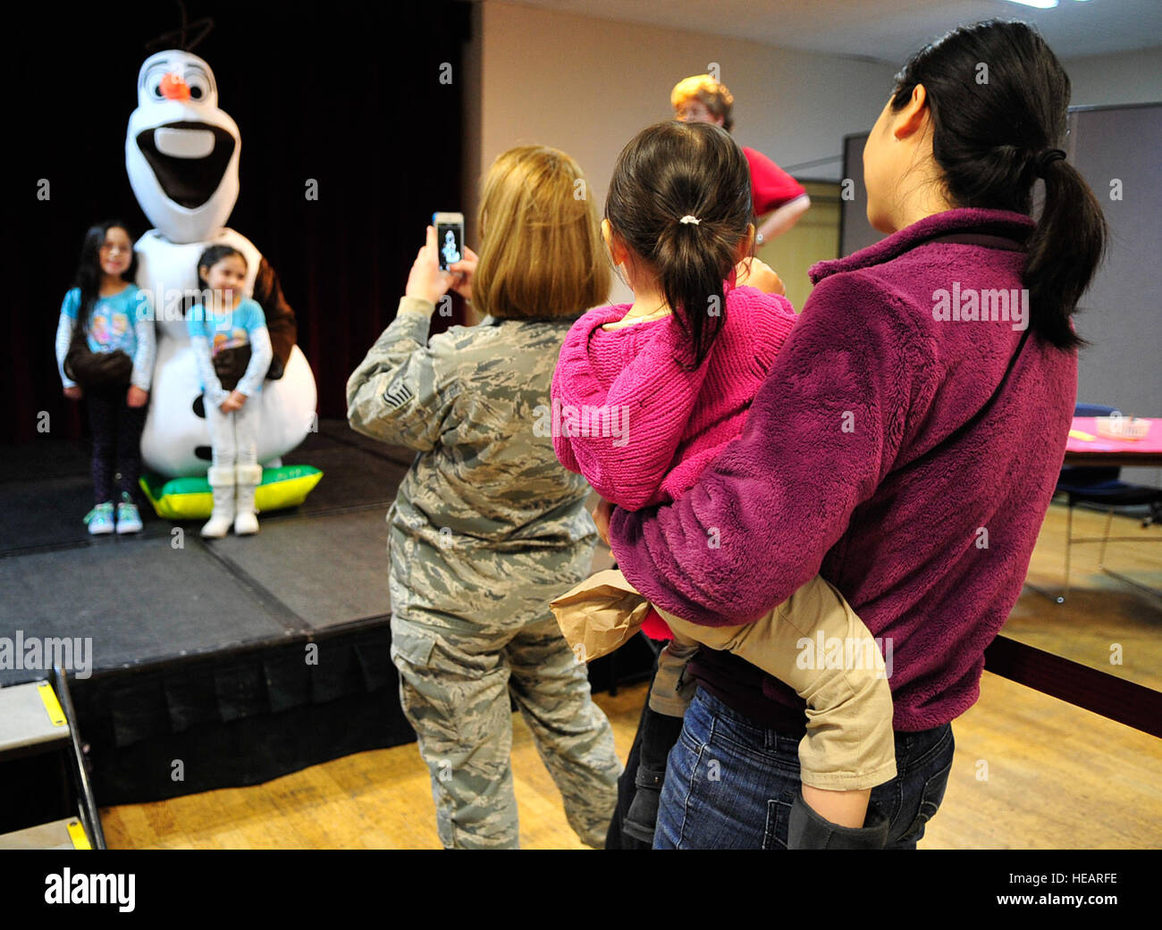 Children and families pose for photos with Olaf during the “Frozen” family event, Jan. 26, 2015 at the Community Center on Ramstein Air Base, Germany. Children and their families had the opportunity to meet one of the movie’s characters, Olaf, as well as make arts and crafts, bounce in the bouncy house and take home balloon animals. Airman 1st Class Larissa Greatwood) Stock Photo
