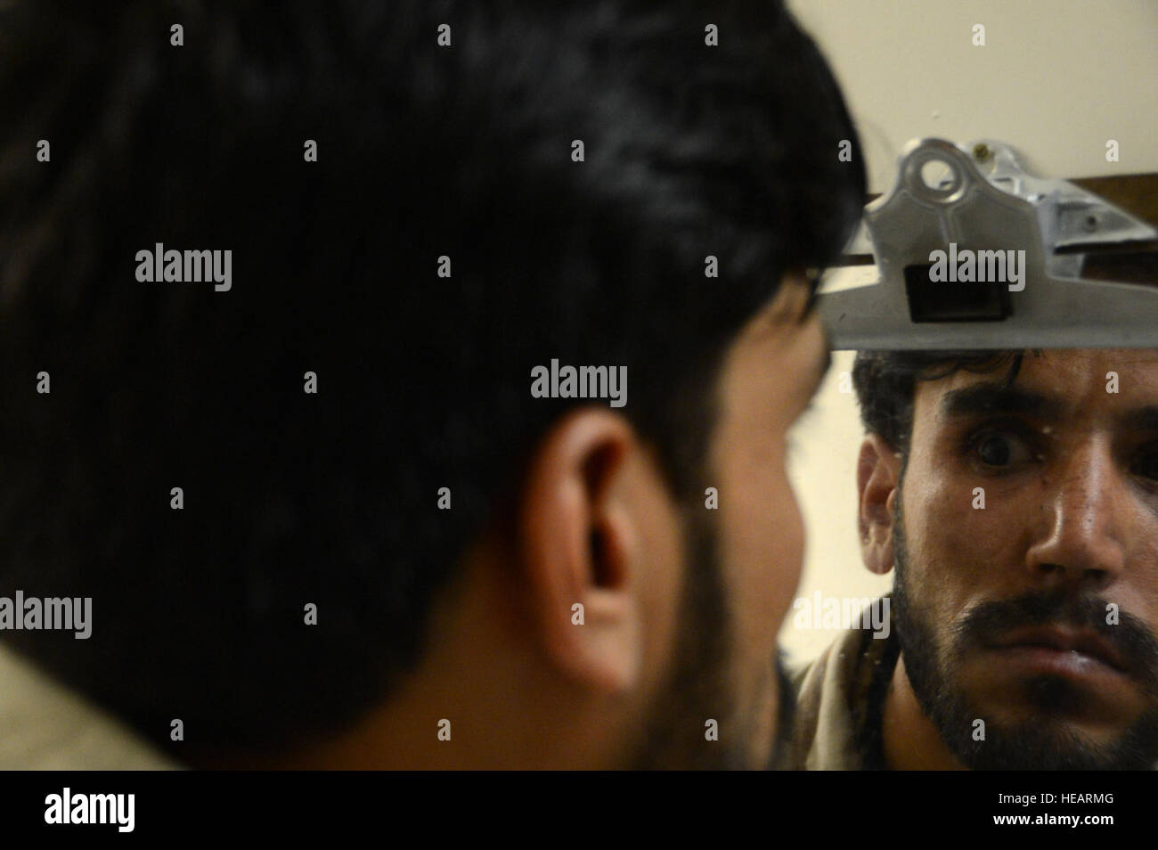 An Afghan soldier looks in the mirror to look at his new prosthetic eye