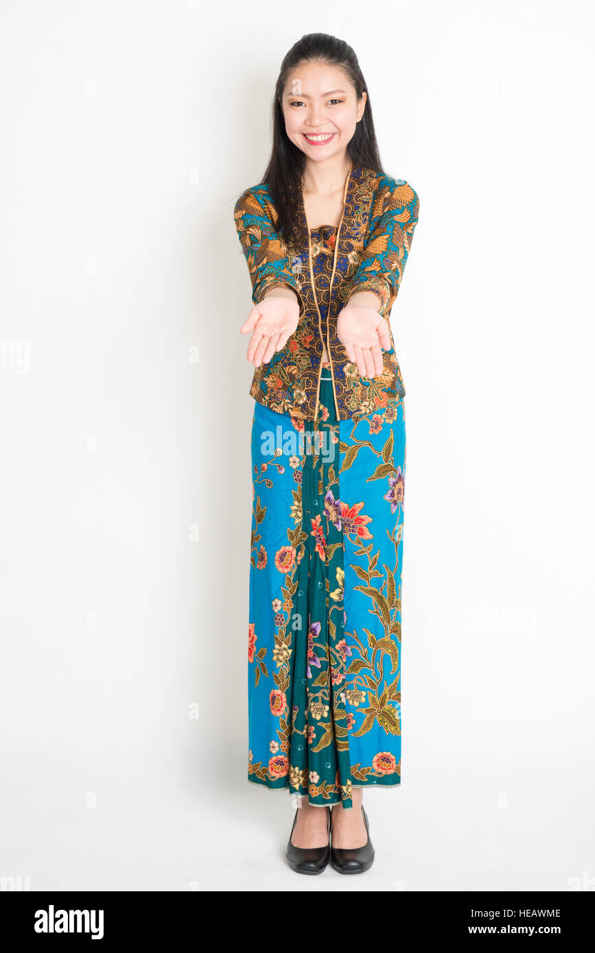 Portrait of young southeast Asian woman in traditional Malay batik kebaya  dress hand holding something, full length standing on plain background  Stock Photo - Alamy