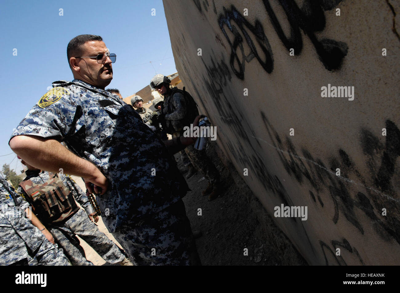 An Iraqi police officer writes through an insurgent's effort to promote propaganda on a school wall, during a cordon and search mission in the Al Siha District of  Mosul, Iraq, May 14. Iraqi police ensures the security of the Iraqi population by clearing and disrupting insurgent activity and showing a presence in neighborhoods throughout the city of Mosul. Stock Photo