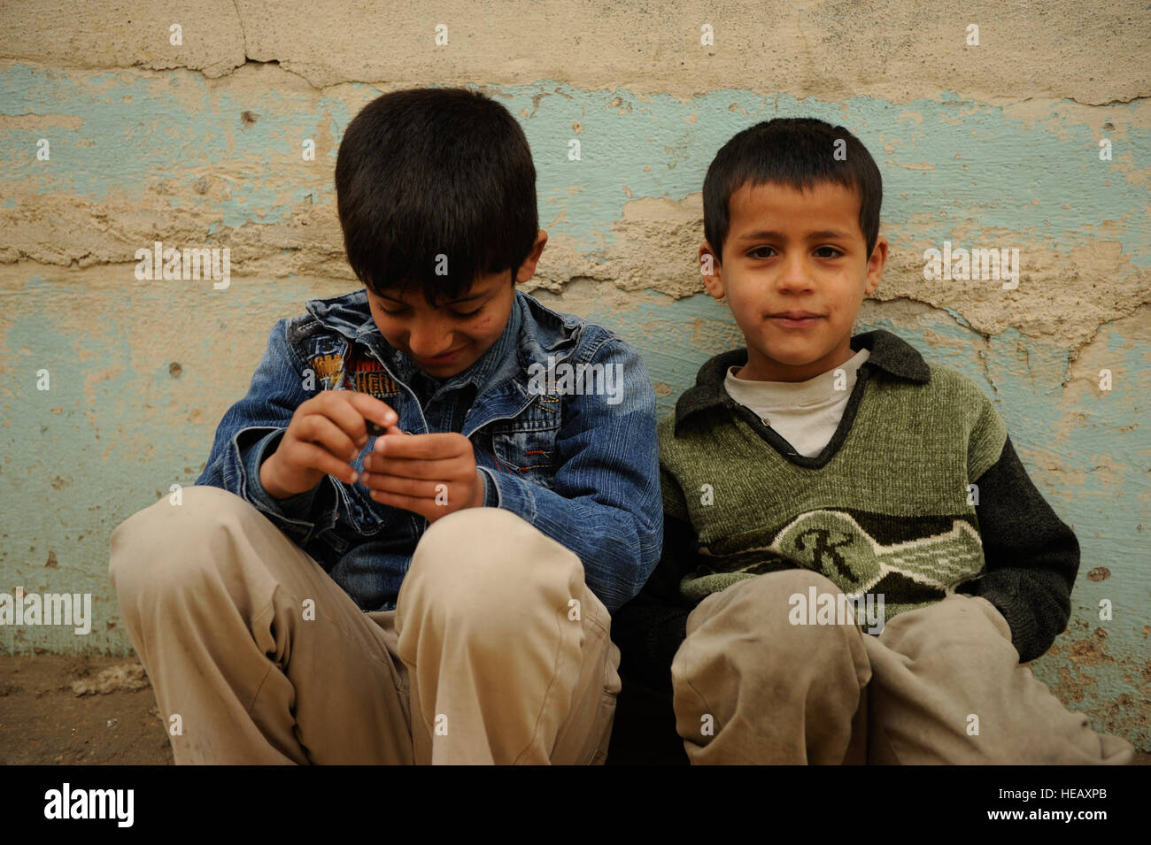 Iraqi children sit outside to watch as U.S. Soldiers from Company A, 3rd Brigade, 8th Regiment, 1st Cavalry Division, and Iraqi national policemen conduct a clearing and census operation in the Zinjali neighborhood of Mosul, Iraq, March 1, 2009. Stock Photo