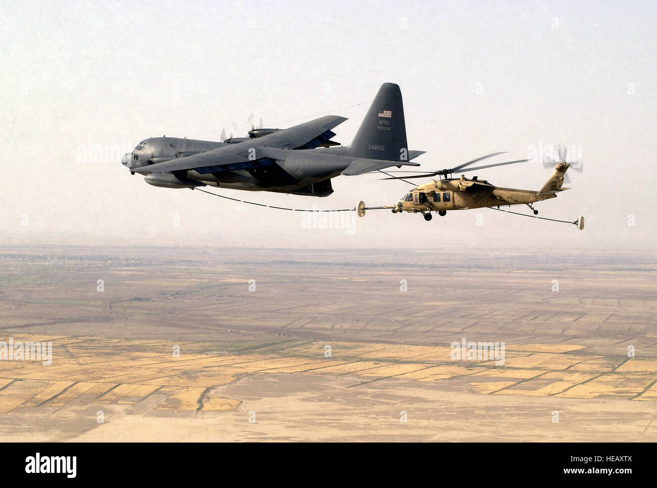 A US Air Force Reserve HH-60G Pave Hawk search and rescue helicopter assigned to the 301st Rescue Squadron, conducts in flight refueling with a Air Force Reserve Command HC-130 Hercules tanker aircraft from the 39th Rescue Squadron, during a mission over Tallil Air Base, Iraq, during Operation Iraqi Freedom Staff Sgt. Shane Cuomo) Stock Photo