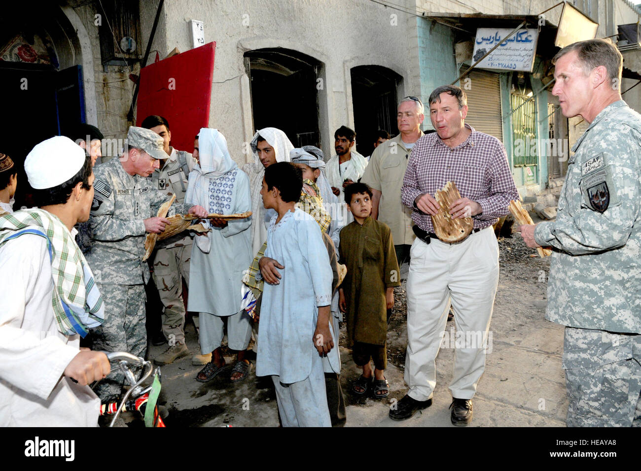 Gen. David H. Petraeus breaks bread with a group of boys outside a bakery in a Kandahar City market  while walking the area Friday (April 30, 2010) with Gen. Stanley McCrystal, International Security Assistance Force commander,  Maj. Gen. Nick Carter, commander of Regional Command - South, (not pictured) and U.S. Ambassador to Afghanistan Karl Eikenberry.  U.S. Army Staff Sgt. Lorie Jewell) (Released) Stock Photo