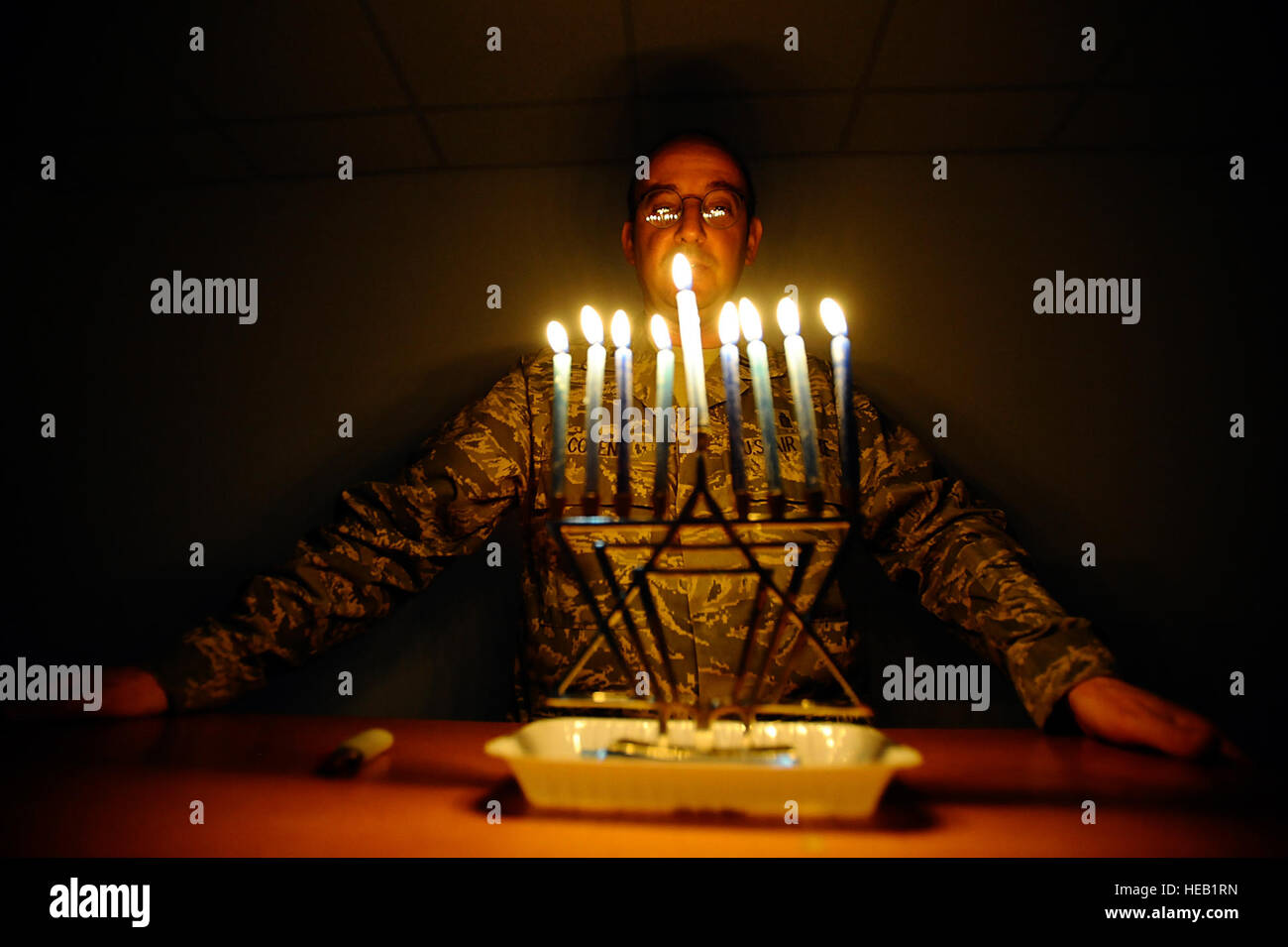 Chaplain (Capt.) Andrew Cohen stands behind a lit menorah during the eighth day of Hanukkah at