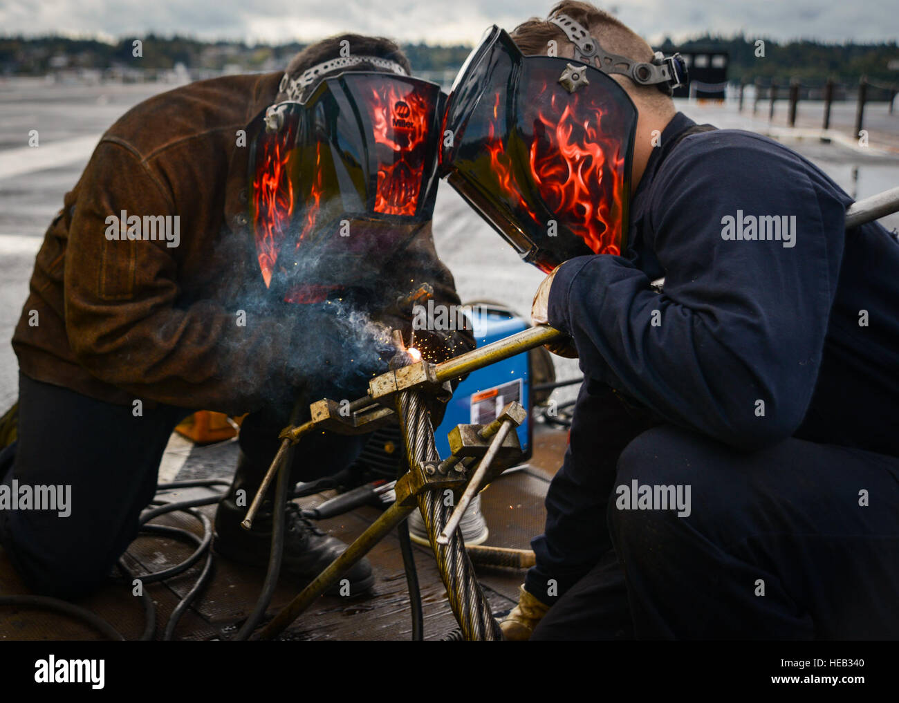NAVAL BASE KITSAP-BREMERTON, Wash. (Oct. 2, 2016) - Seaman Chase Ethridge (right), a native of Katy, Texas, steadies an arresting cable while Petty Officer 3rd Class Gabriel Moreno, a native of Huntington Beach, Calif., welds during a reweave of the arresting gear on board USS Nimitz (CVN 68). Nimitz is currently undergoing an extended planned incremental maintenance availability at Puget Sound Naval Shipyard and Intermediate Maintenance Facility where the ship is receiving scheduled maintenance and upgrades.  Petty Officer 3rd Class Samuel Bacon Stock Photo