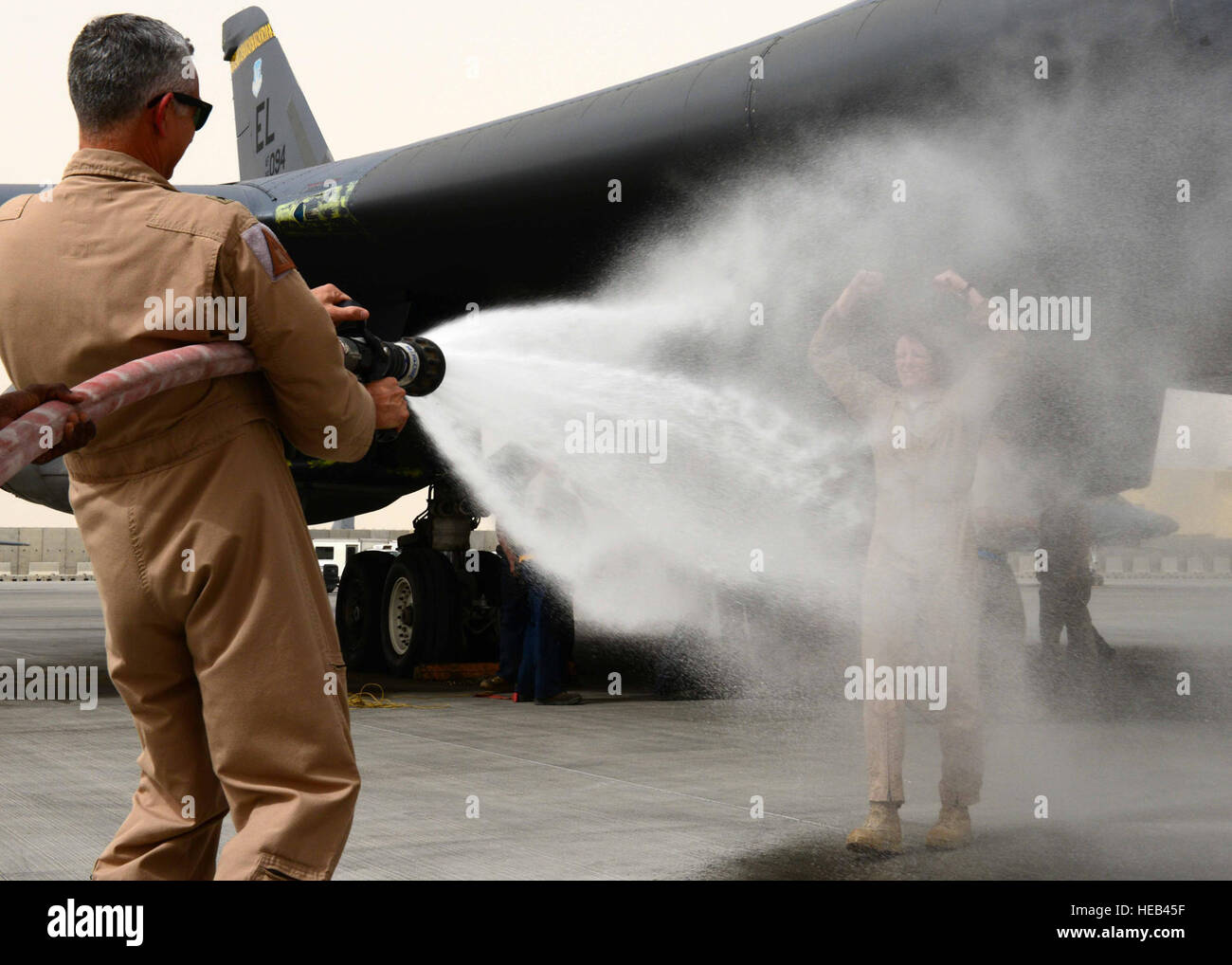 U.S. Air Force Brig. Gen. Roger H. Watkins, 379th Air Expeditionary Wing commander, sprays Col. Jennifer Fullmer, 379th AEW vice commander after a fini flight at Al Udeid Air Base, Qatar, May 11, 2013. The USAF has a tradition where aircrews, on the completion of a final flight in an aircraft, are hosed with water by their comrades before being toasted. Watkins is from Fort Worth, Texas. Fullmer hails from Wilton, Conn.  Staff Sgt. Ciara Wymbs) Stock Photo