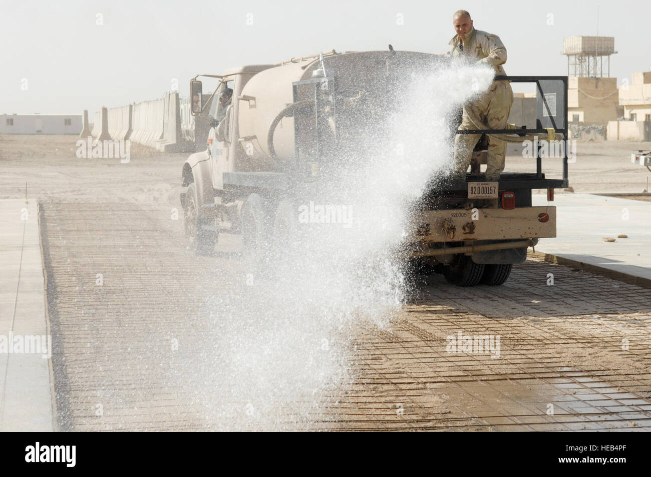 Senior Airman Carl Perkins, a 'Dirt Boy' from the 407th Expeditionary Civil Engineer Squadron (ECES), Ali Air Base, Iraq, sprays down the road before his team begins to lay cement for a pad at Camp Mittica, Iraq, on June 11, 2007.  The 407th ECES is on the Iraqi base building a 220 foot by 200 foot cement drill pad that will be used by the Iraqi army to train their enlisted soldiers. Stock Photo