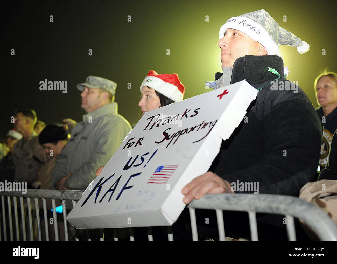 A U.S. Navy member from the NATO Role 3 Multi-National Medical Unit holds a sign during the USO morale event Dec. 16 at Kandahar Air field, Afghanistan. Thousands of NATO service members attended the event which included several high-profile celebrities such as actor Robin Williams, comedians Lewis Black and Kathleen Madigan, musicians Kix Brooks and Bob Dipiero, and athlete Lance Armstrong. U.S. Navy Adm. Mike Mullen, chairman of the Joint Chiefs of Staff, provided opening remarks for the event. Stock Photo